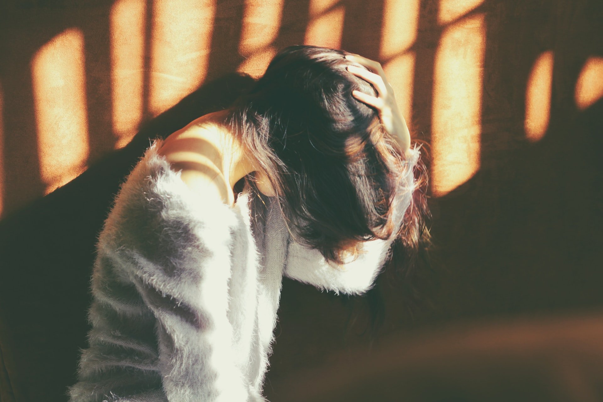 An upset woman holding her head in her hands | Source: Unsplash